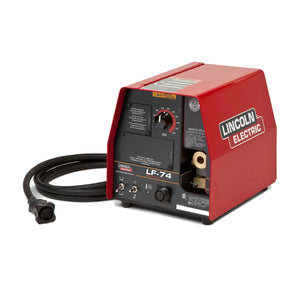 A red Lincoln LF-74 Wire Feeder, Base Model K2426-4, for MIG welding rests on a white background. It features a control panel, black adjustment knob, multi-pin connector cable, and displays the prominent Lincoln Electric logo.