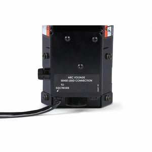 Close-up of the Lincoln MAXsa 29 Feed Head K2312-2, a black electrical device labeled ARC VOLTAGE SENSE LEAD CONNECTION TO ELECTRODE. A black cable extends from the left; four screws are on the front panel, with a plain white background.