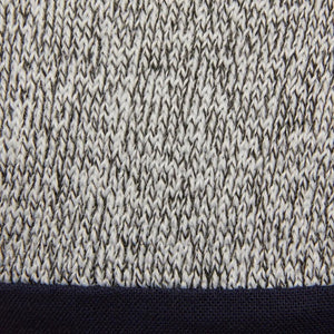 Close-up of a marled knit fabric in white and black forming a zigzag pattern, with a solid dark blue band at the edge—similar to the reinforced cuffs on Lincoln MX Series Premium A4 Cut Resistant MIG Gloves XL K5131-XL for extra durability.