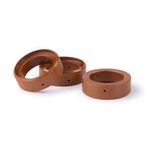 Three brown, circular, hollow rings with smooth surfaces are placed on a white background. These could be Lincoln plasma consumables, featuring small holes on their sides and arranged with one slightly leaning against another.