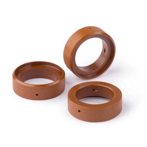 Three brown, circular, hollow rings made of a smooth material are shown on a white background. Each ring has a small hole on the side. These Lincoln plasma consumables are arranged with one standing upright and two laying flat.
