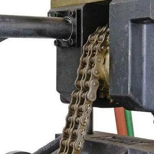 A close-up of a metal chain being manufactured or repaired by an industrial machine, with the chain partially looped through the equipment. The background is plain white.